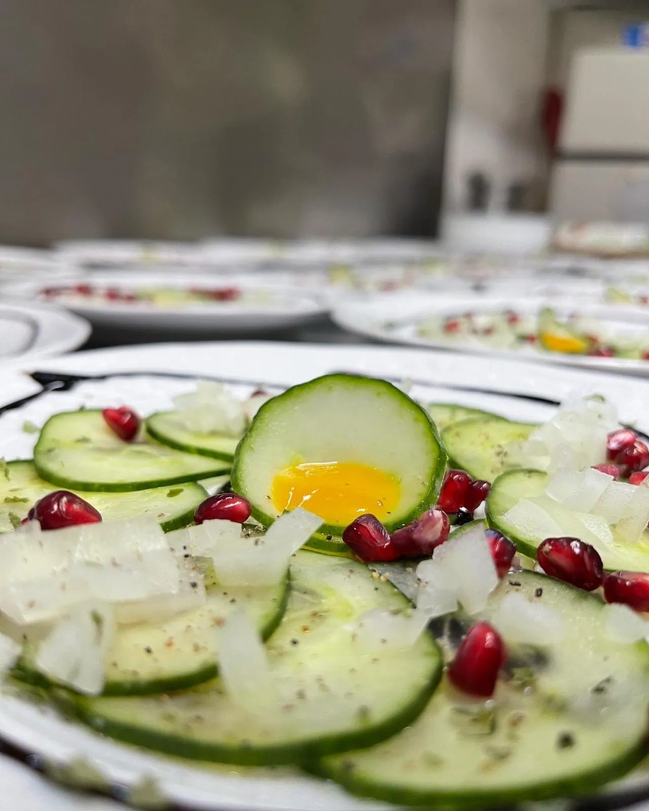 Gurken-Carpaccio mit Eigelb, Granatapfel und Zwiebeln, frisch angerichtet